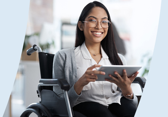 Une personne souriante qui tient une tablette électronique, assise dans un fauteuil roulant.